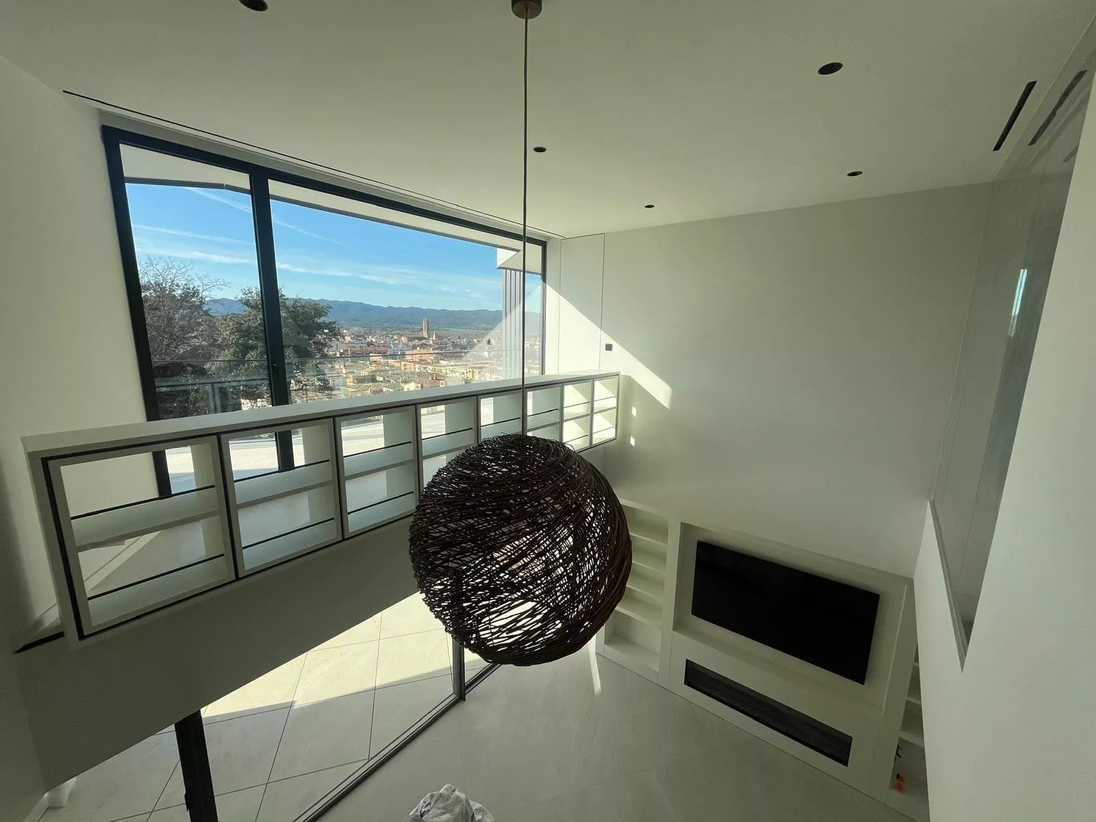 Diseño interior moderno de casa BBE con vistas panorámicas, gran lámpara de mimbre y estanterías a medida.