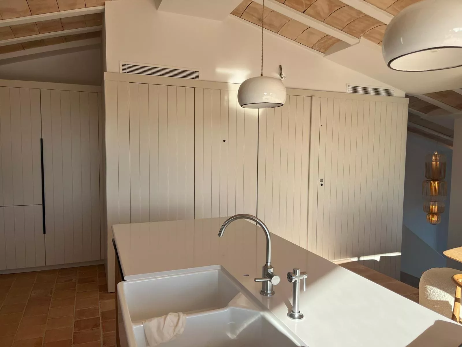 Cocina moderna con isla central, fregadero de cerámica y grifo de acero inoxidable, armarios de madera a medida.