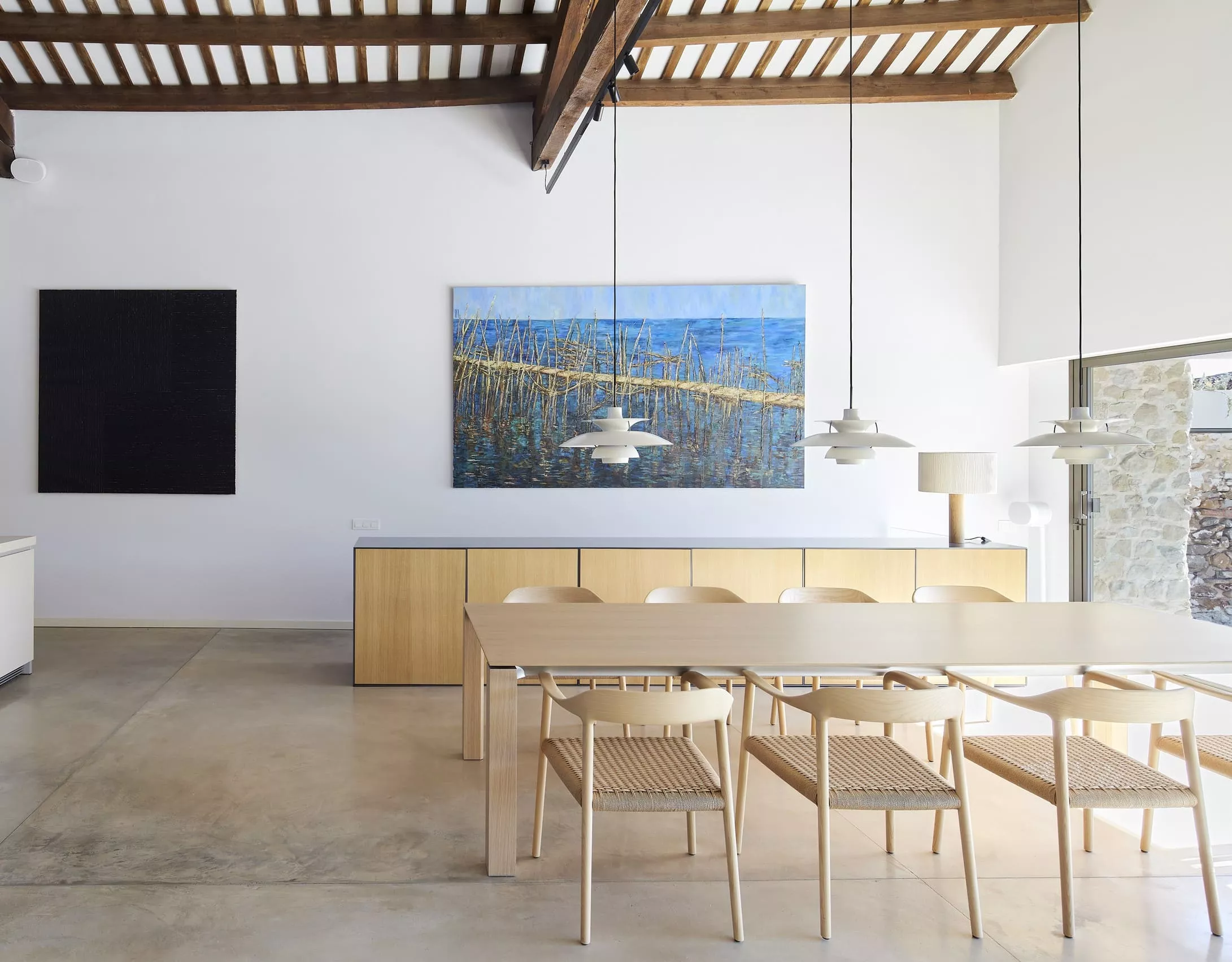 Comedor de diseño moderno en Casa GBE con mesa de madera clara, sillas de mimbre y arte contemporáneo.