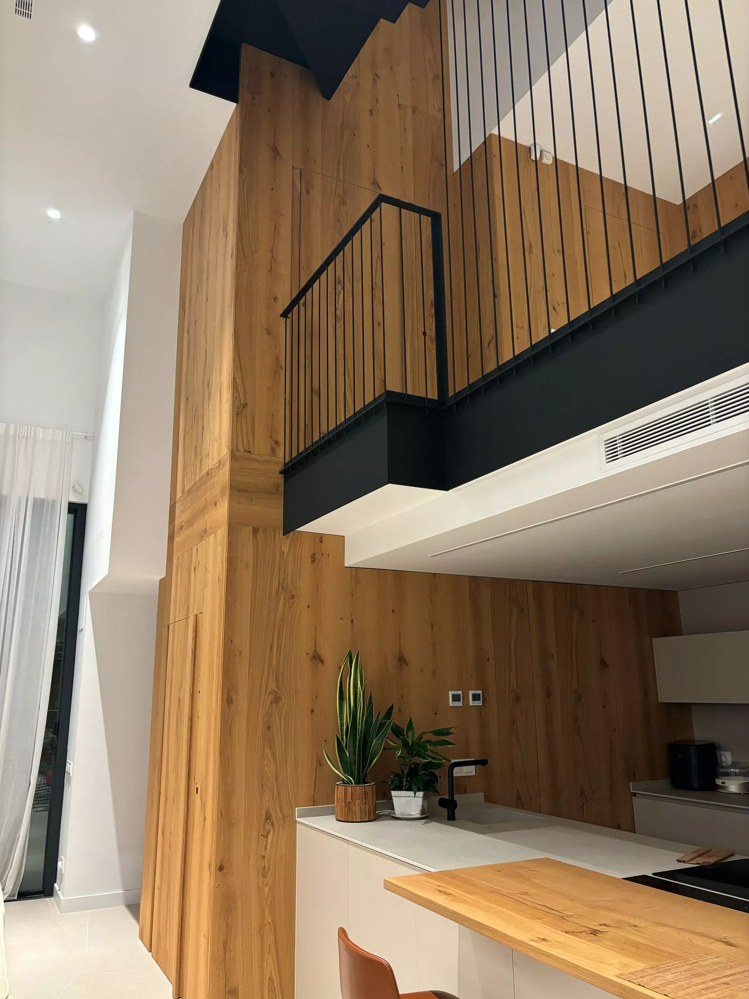 Cocina moderna con isla de madera y pared de listones de madera, destacando la carpintería a medida y diseño interior.