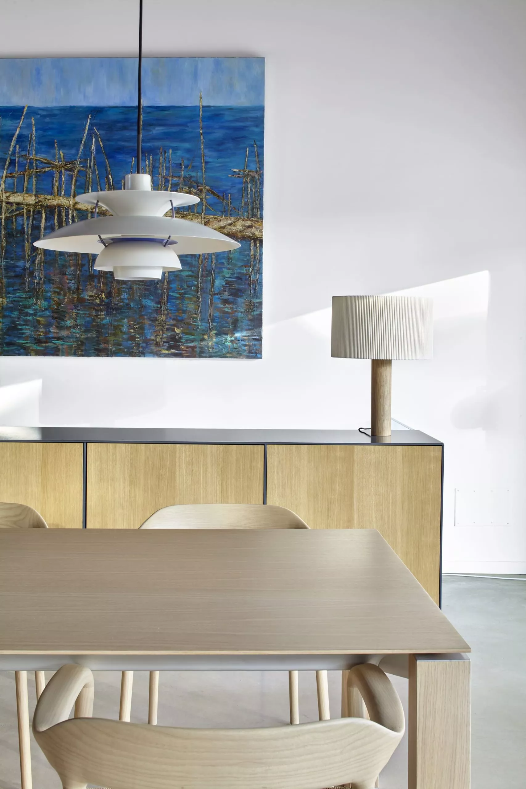 Comedor moderno con mesa y sillas de madera clara, lámpara de diseño y aparador de carpintería a medida