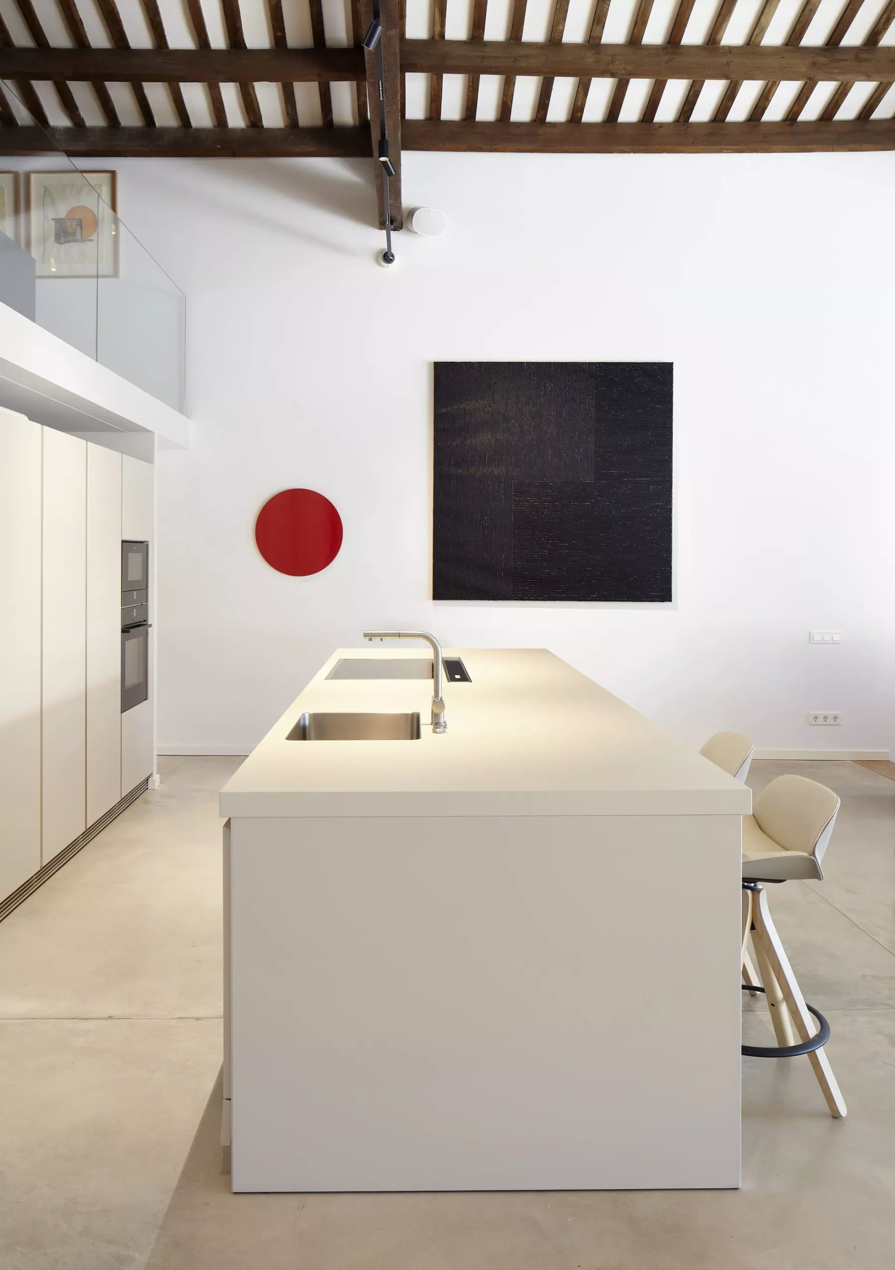 Cocina moderna con isla central, fregaderos integrados y taburetes, destacando la carpintería a medida y diseño interior.