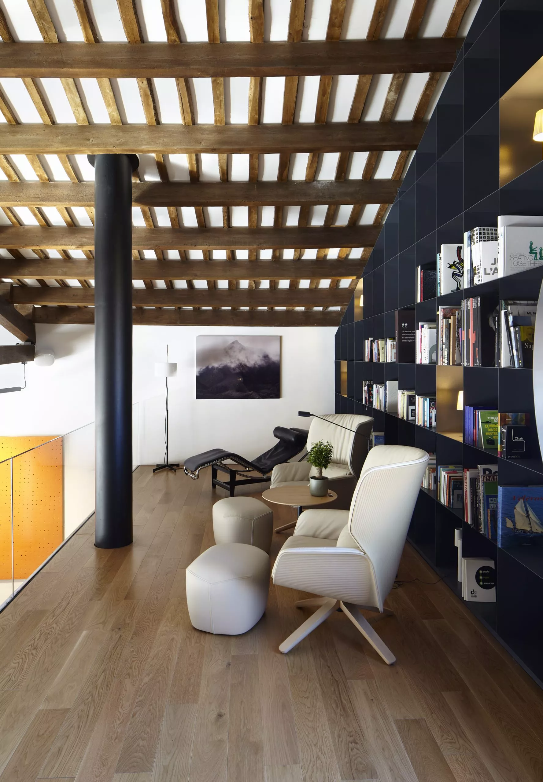 Salón moderno con techo de vigas de madera, estantería negra y mobiliario de diseño, reflejando la pasión por la madera.